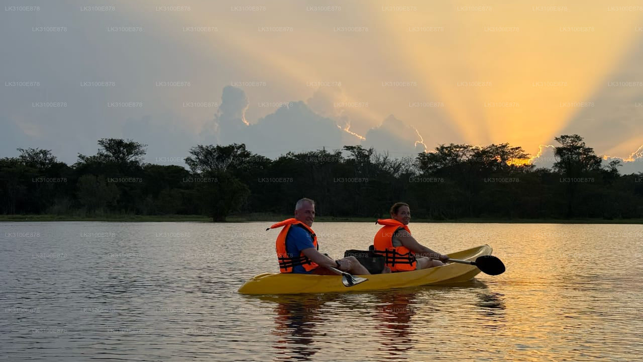 Two people in a kayak on a lake with a sunset in the background