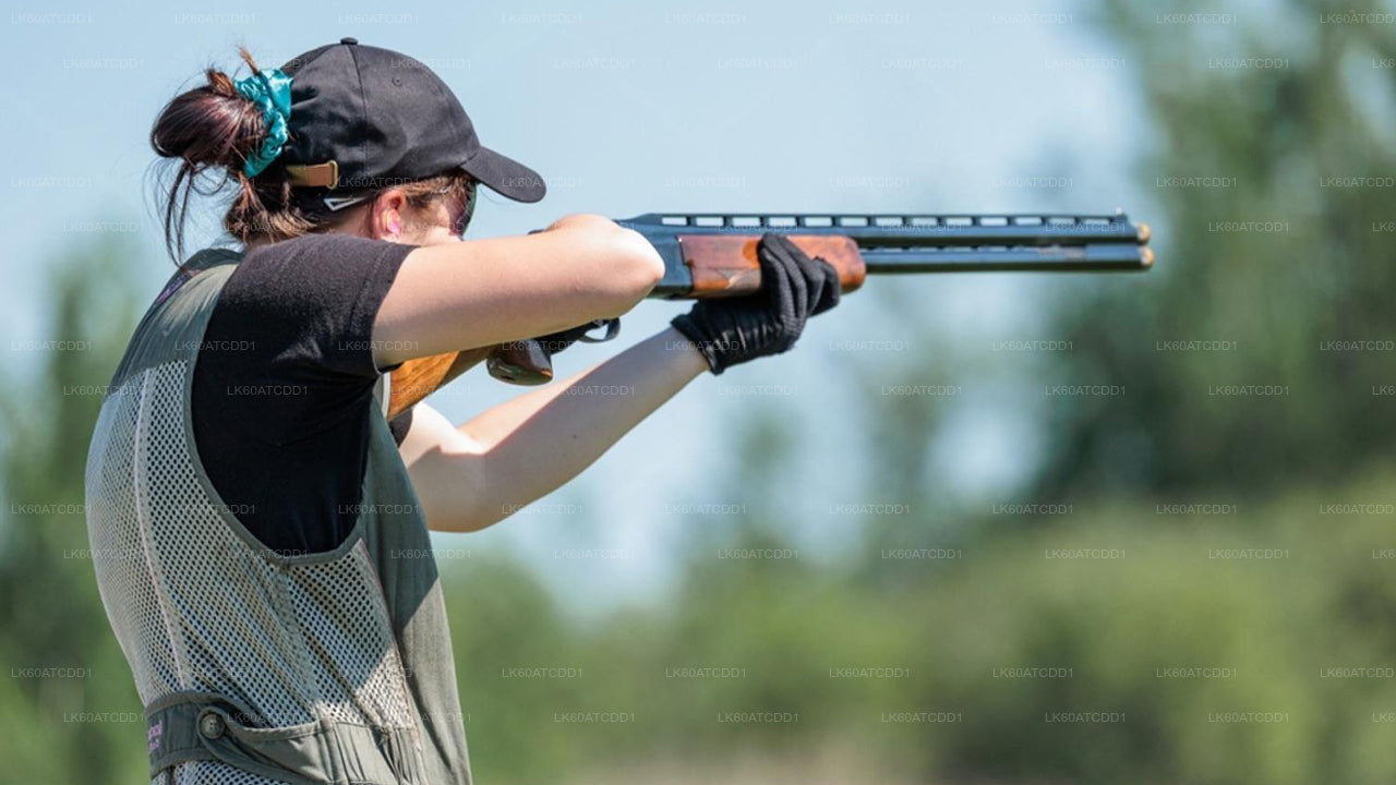 Person in protective gear holding a shotgun outdoors with a blurred natural background